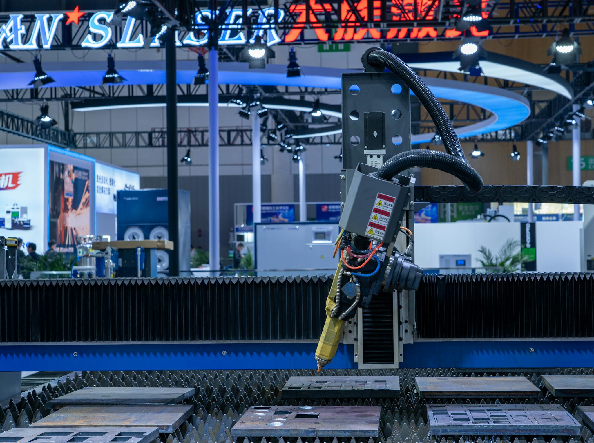 A CNC laser machine operating in a high-tech industrial exhibition setup with vibrant lighting.